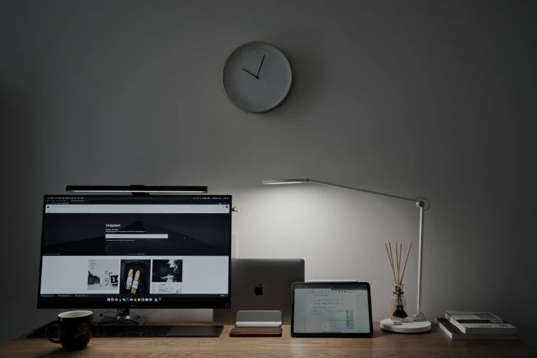 two computers, one large and one small, sitting on top of a desk