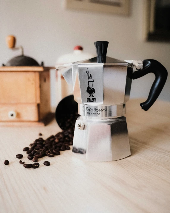 a white and black coffee pot next to some coffee beans