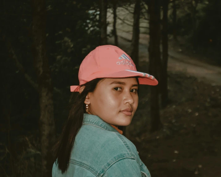 an asian woman wearing a pink adidas cap and denim jacket