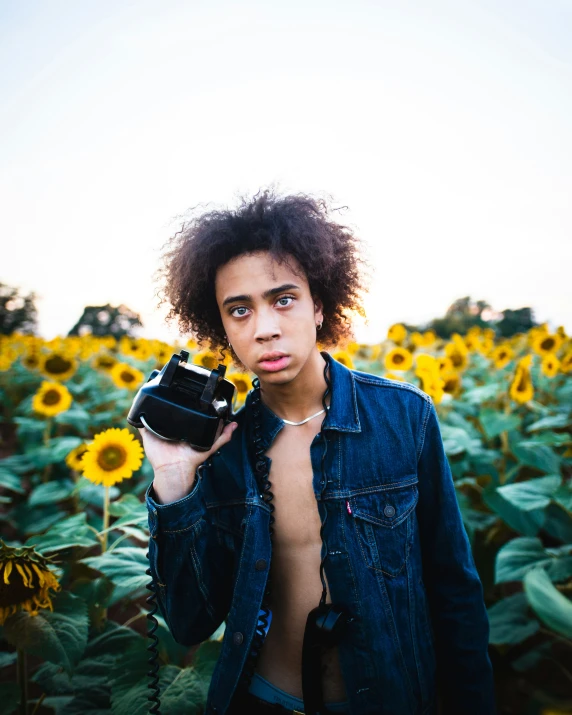 a man holding up a camera next to a sunflower