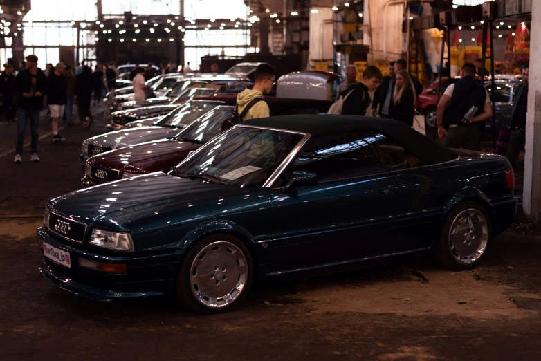 many people stand beside an empty car