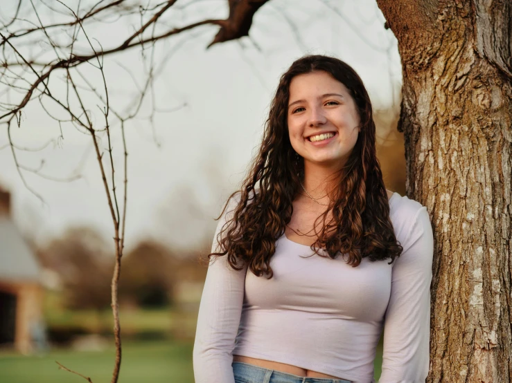 a woman smiling next to a tree and building