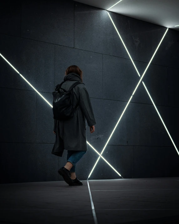 person walking along concrete in dark lit space