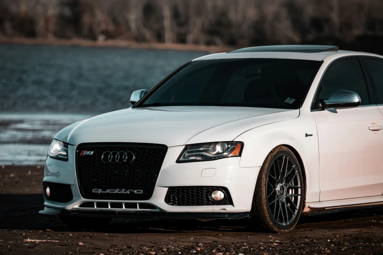 the front end of a white audi rs5 parked near the ocean