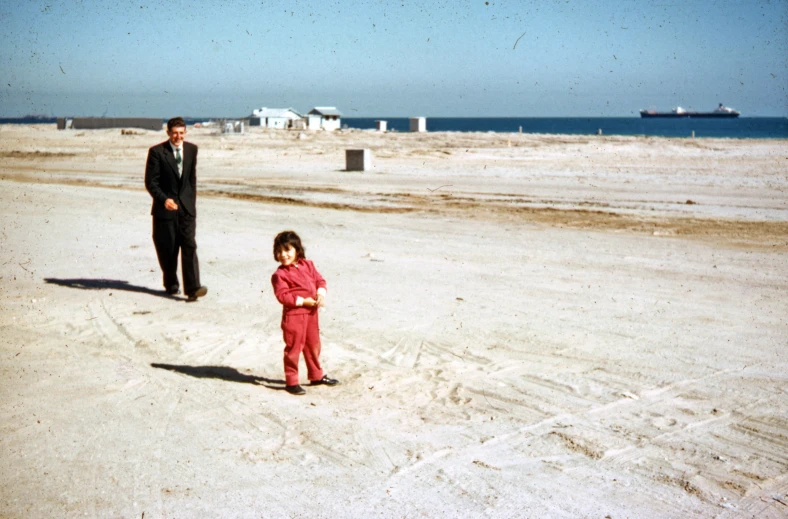 there are two people standing in the sand by the ocean