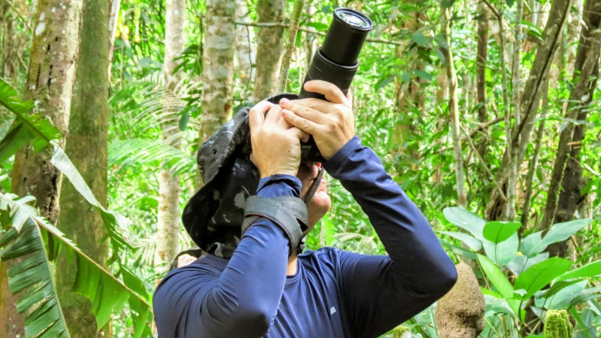 a person is holding a camera in front of their head with the camera lens on