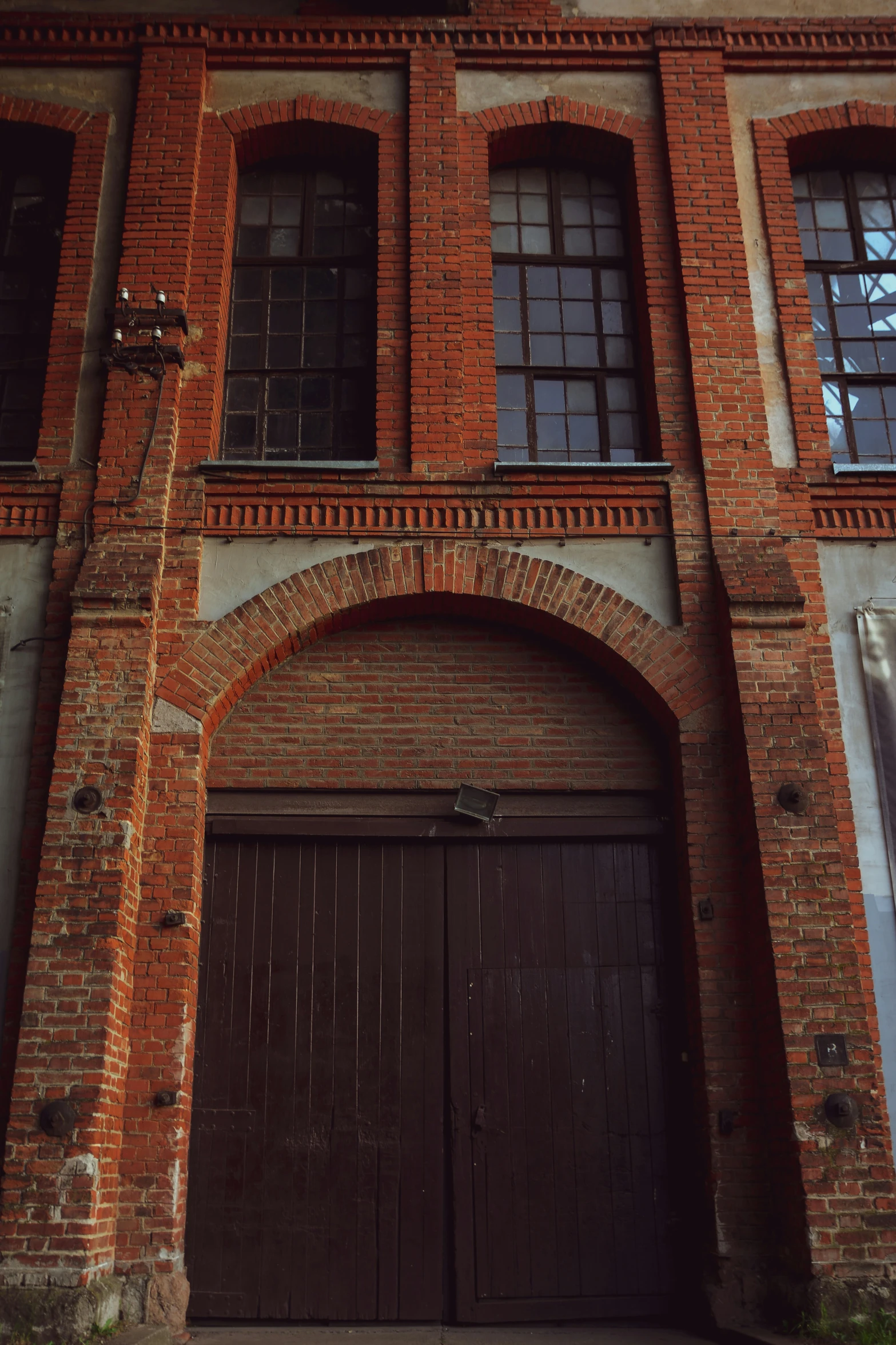 the two brown doors are in front of the brick wall