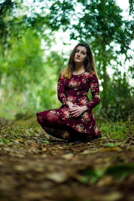 a woman sitting in the middle of a forest