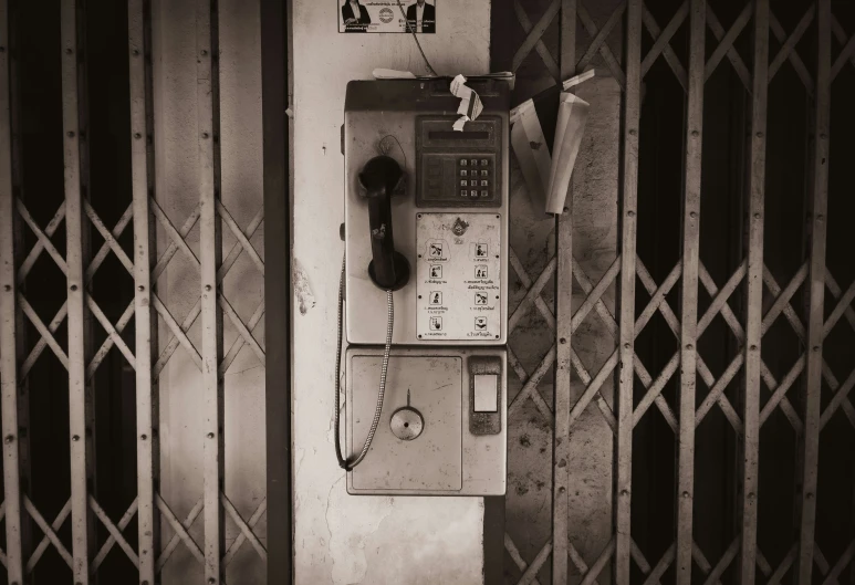 a vintage pay phone sits in front of an old fence