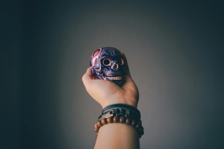 someone holding a skull mask on their wrist