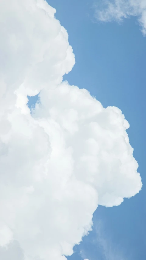 a plane flying on a cloudy day with some clouds in the background