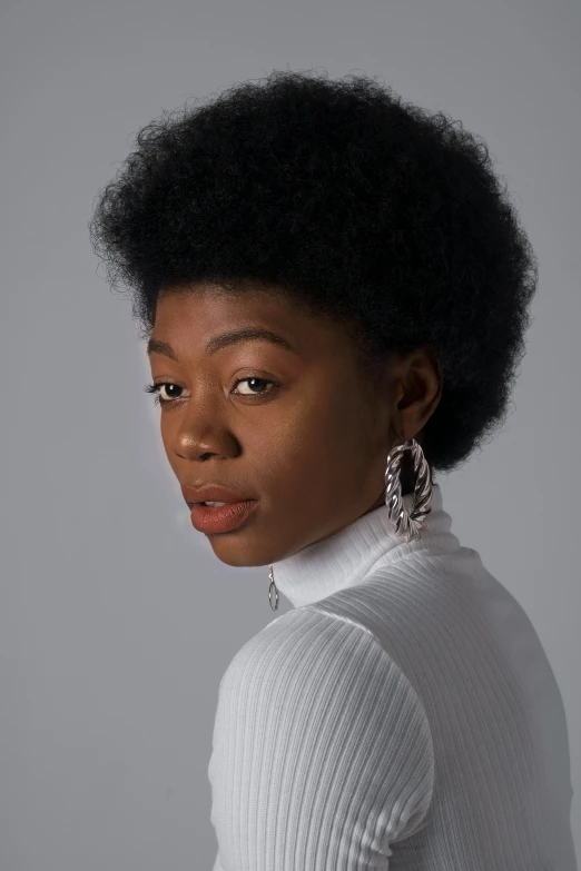 a woman in a white sweater wearing large earrings