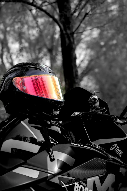 a motorcycle with its red helmet sitting up against a tree