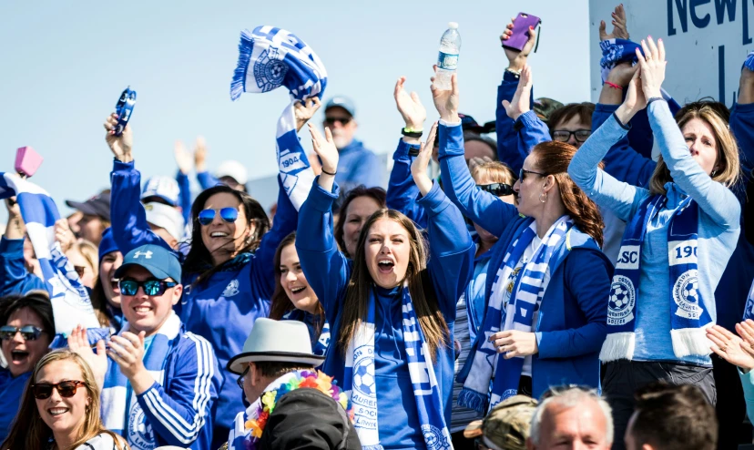 several women at a sporting event cheer and wave