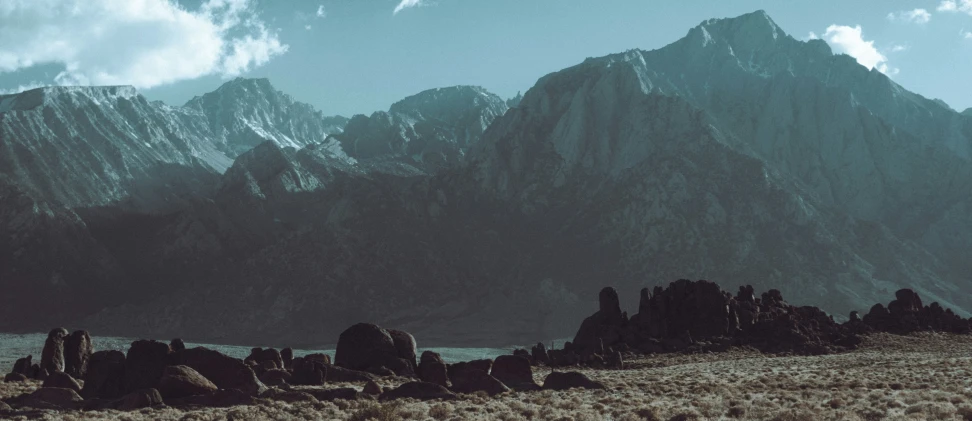 the large mountains are towering up high above the water