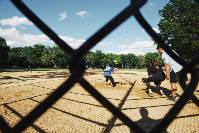 s are playing baseball in a park through a fence