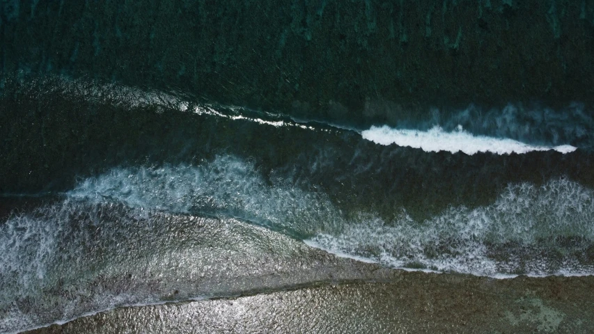 an aerial view of the ocean with a white surf