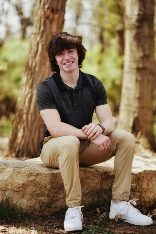 a young man in a polo shirt sitting on a rock