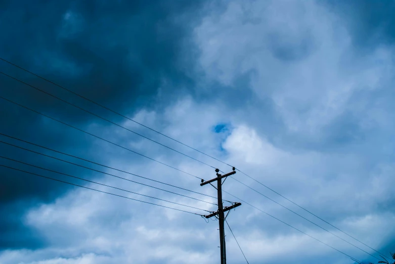 an electrical pole with many wires connected under a cloudy sky