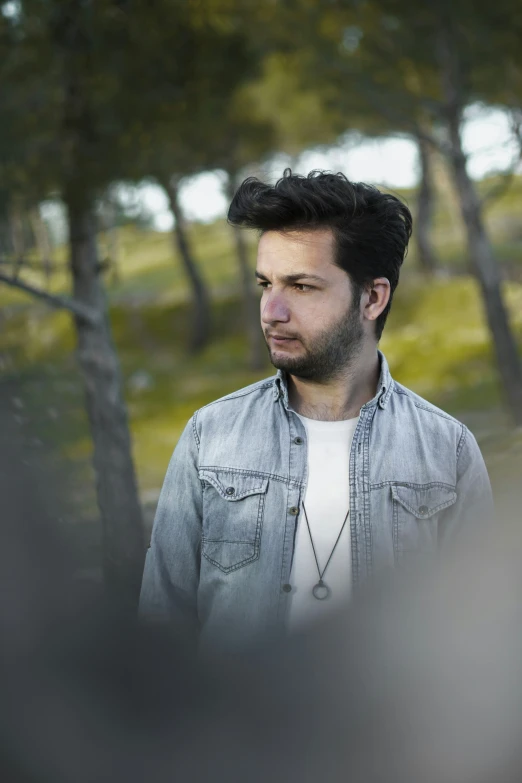 a man with dark hair wearing a jean jacket