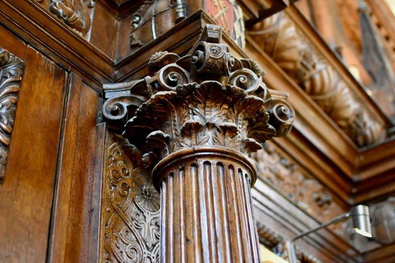 an ornate wooden column against a brown wall