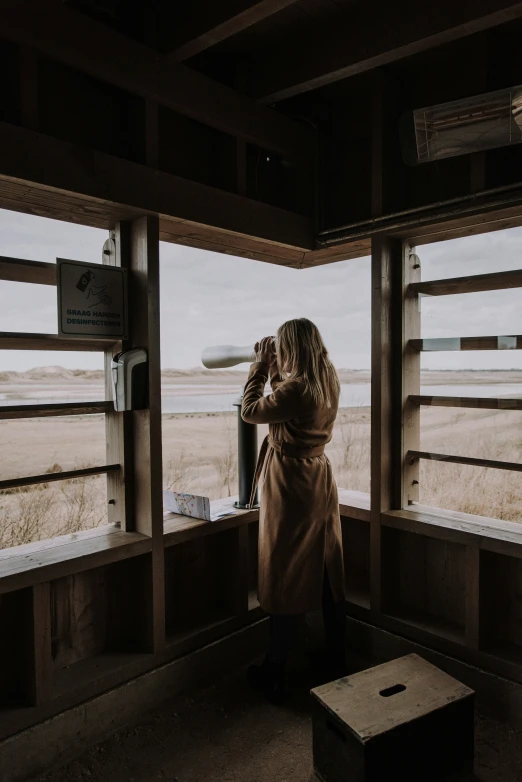 a woman is looking out the windows at an open field