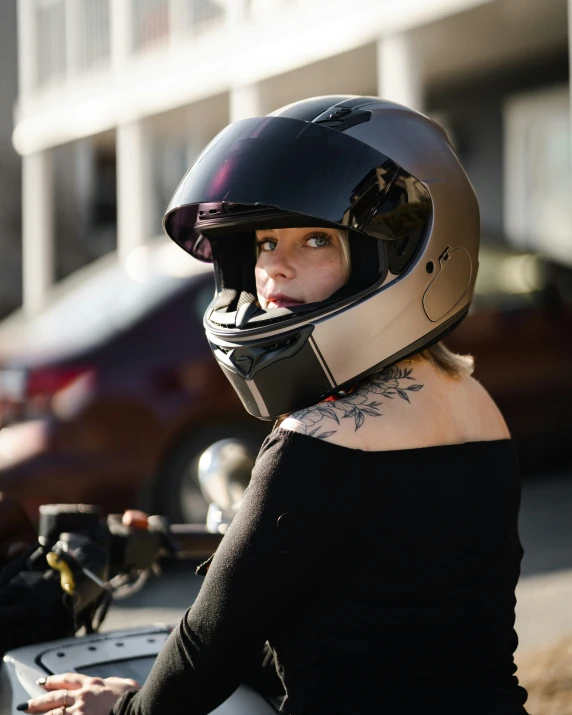 a woman with a tattoo on her back sitting on a motorcycle