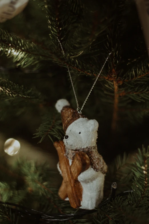 teddy bear with scarf is perched in the top of the tree