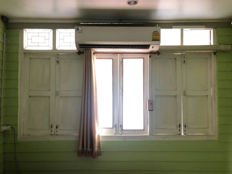 a green room with white windows and an air vent