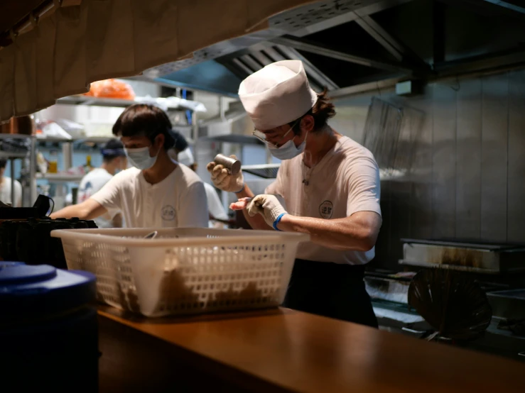 chefs wearing protective masks in a kitchen cooking food