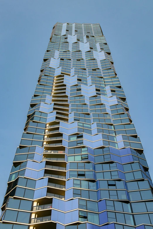 a tall blue glass building with a very high rise