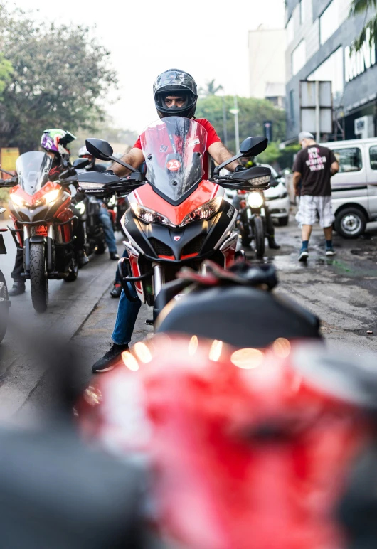 man on red motorcycle surrounded by bikers and cars