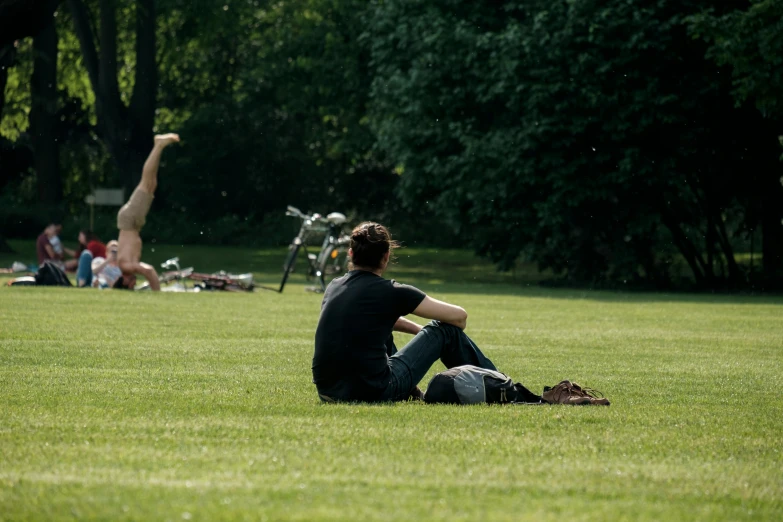 there is a man sitting in the grass near a bicycle