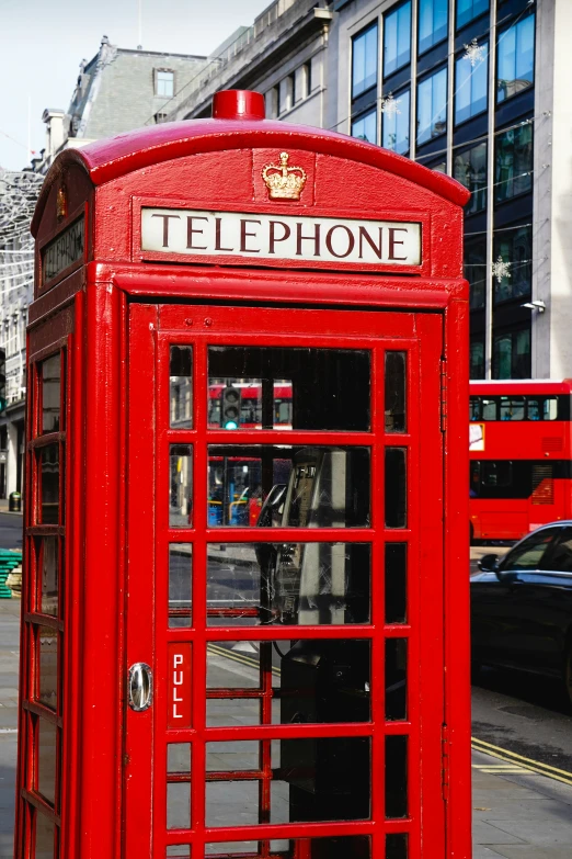 an old - fashioned red telephone booth on the side of the road