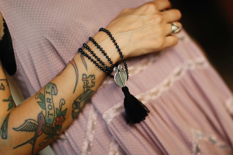 a woman with tattoos wearing a beaded tassel celet