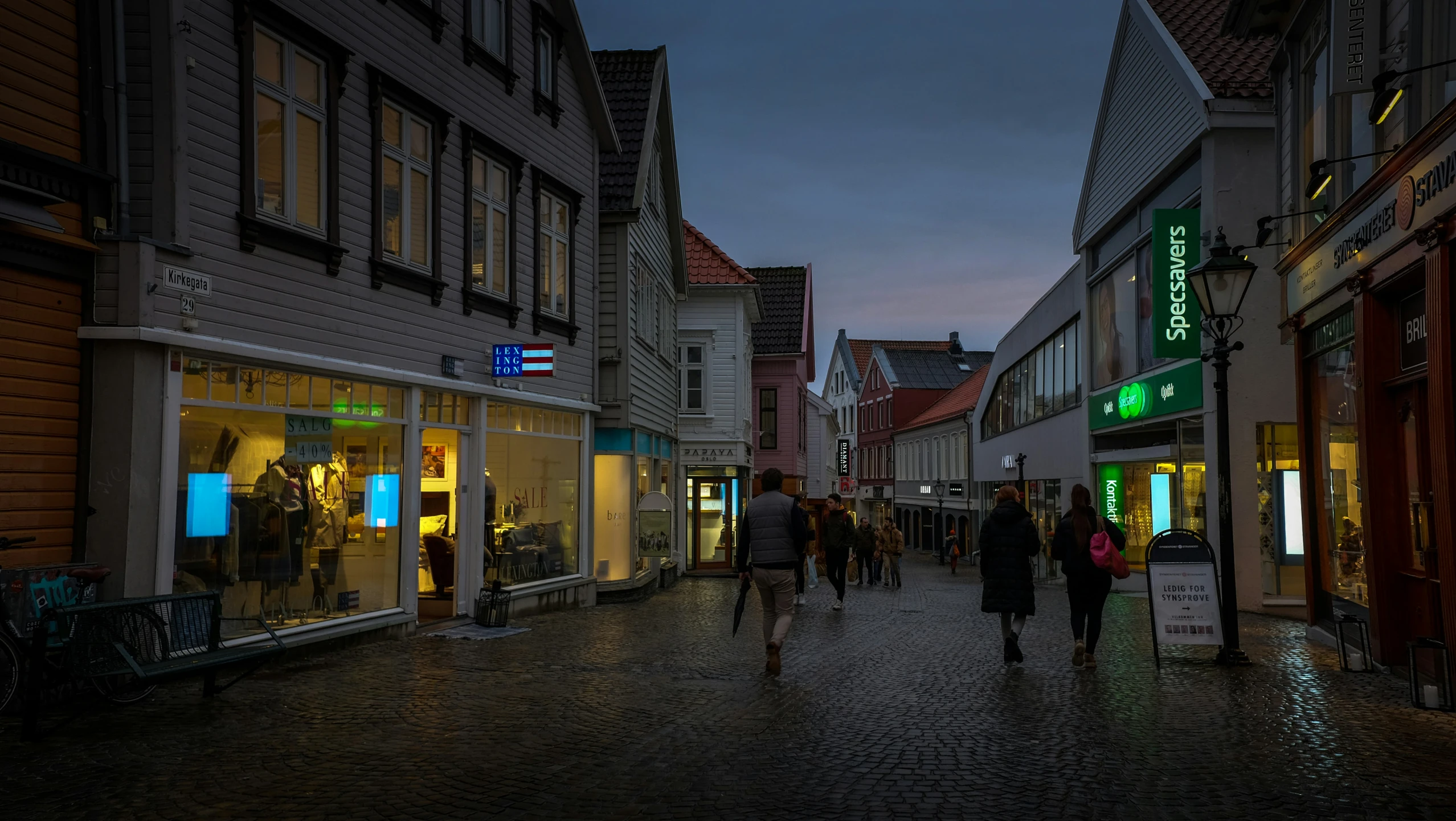 a city street at night with pedestrians and shoppers
