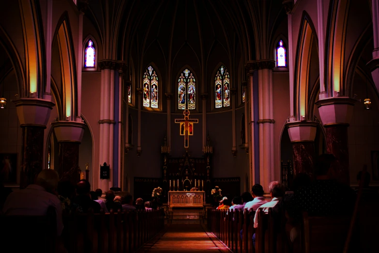 people sitting in pews looking at the stained glass windows