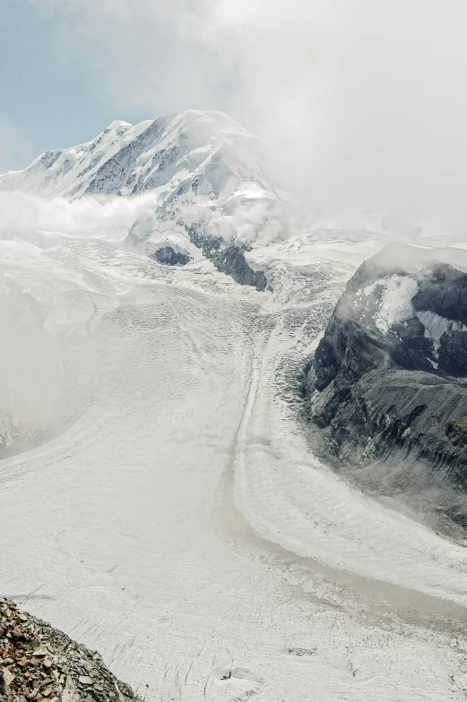 a person in yellow jacket looking down at a snowy mountain range