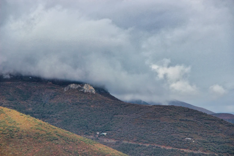 a small mountain with a forest and mountain covered by clouds