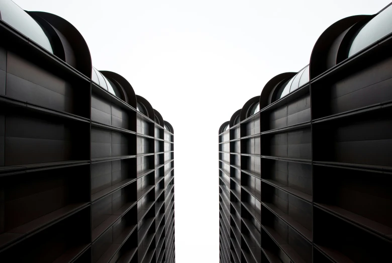 the rears of two black buildings against a white sky