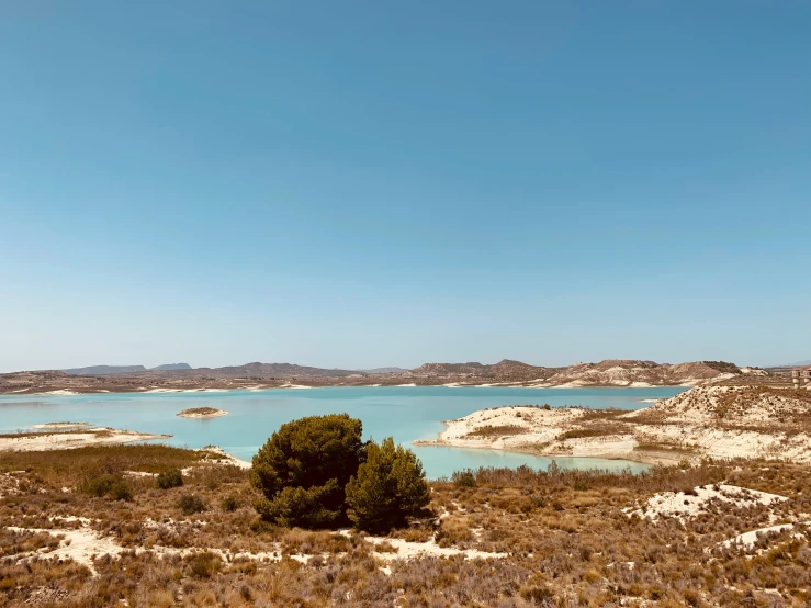 an unpaved view of a blue water reservoir surrounded by brush