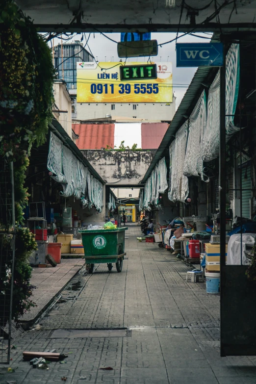 an alley with a sign and trash bin on the sidewalk