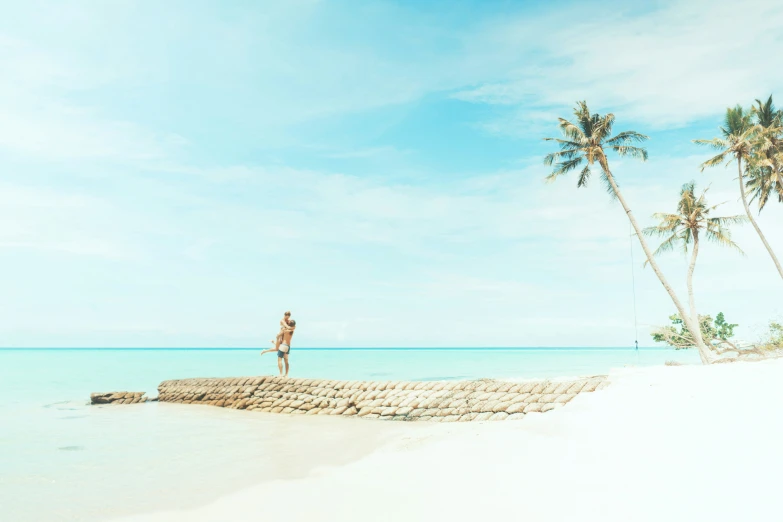 a person standing on the edge of a stone wall by the ocean