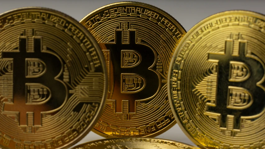 three gold bitcoins sit next to each other