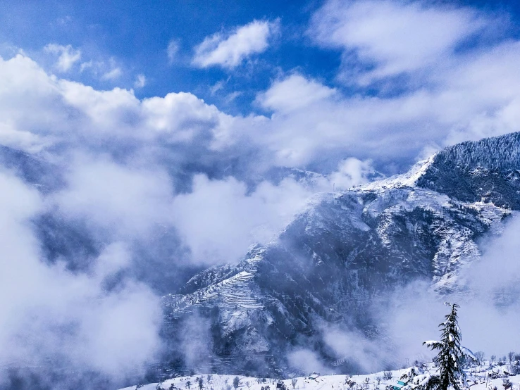 snow covered mountains, clouds and some trees