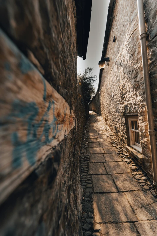 a narrow street between two brick houses with a wooden railing