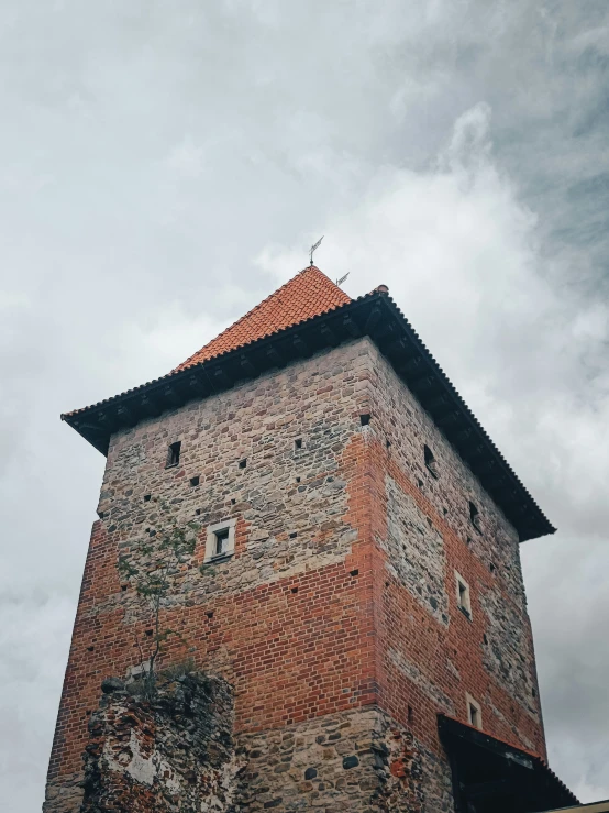 a tall brick building with a weather vane and red roof