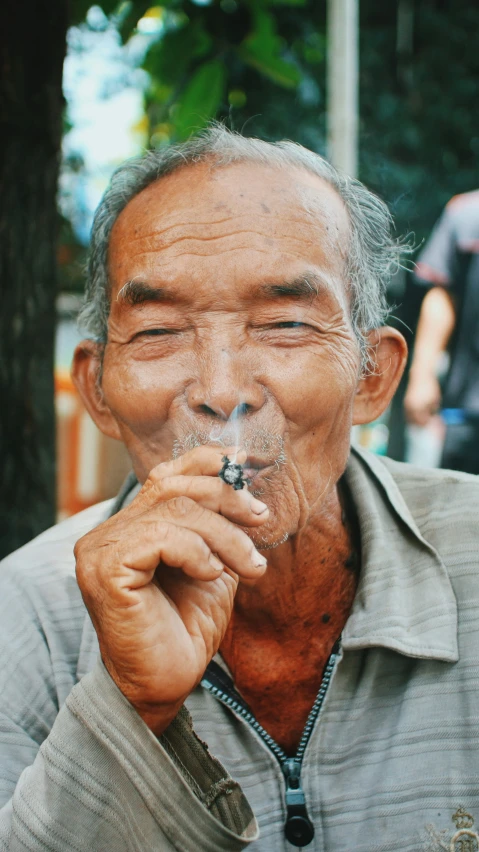an older man holding a cigarette and smiling for the camera