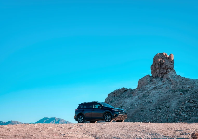 a black car parked in front of a rocky mountain