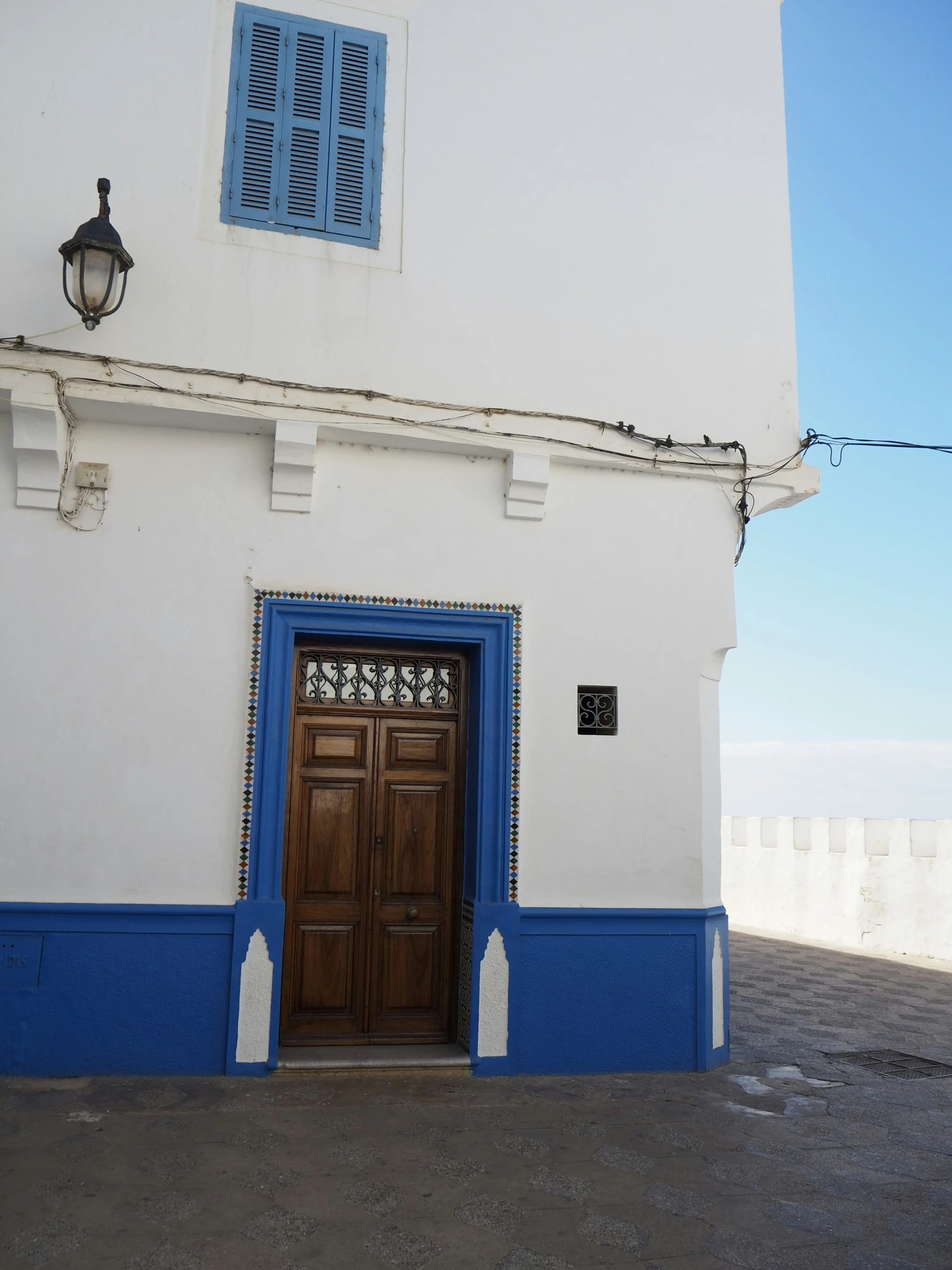 a blue door on an old building with a blue shuttered window